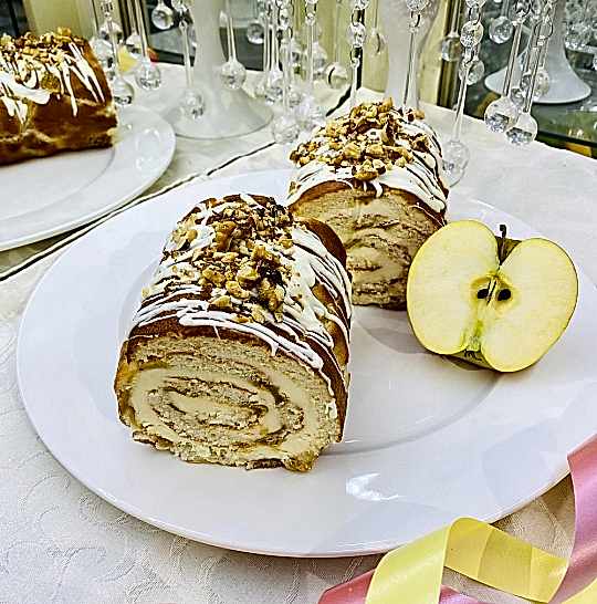 Рулет яблочный с сырным кремом. Оформлен белым шоколадом и грецким орехом.